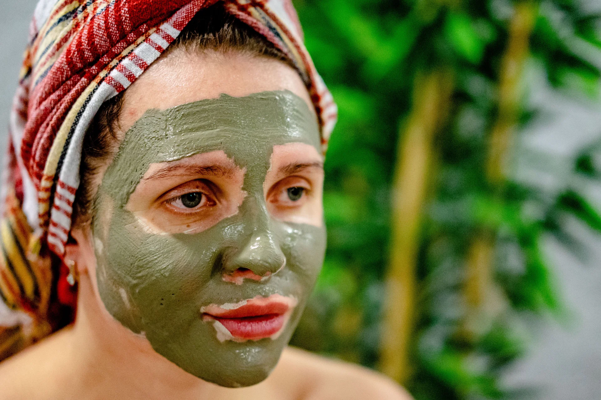 Kobieta relaksuje się z maseczką błotną na twarzy w spa, dbając o skórę.